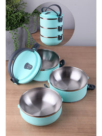 A mint green stackable lunch box with three tiers and a dark gray lid, set on a marble countertop