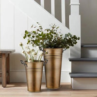 A gold-colored galvanised steel vase with two handles, suitable for indoor and outdoor use.