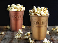 A gold galvanised steel popcorn bowl with the word 'POPCORN' embossed on the side.