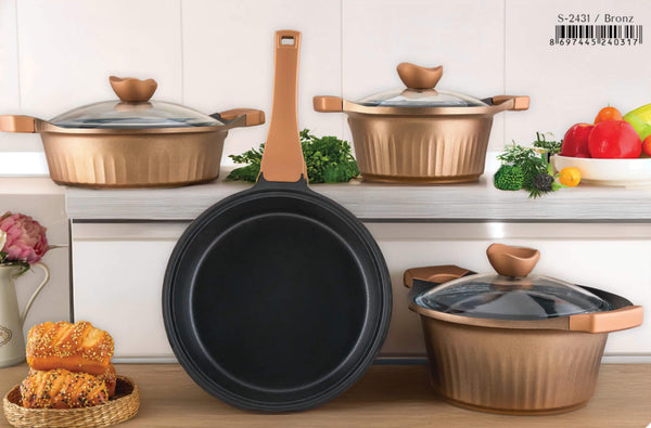 Set of cookware including a black frying pan and copper pots on a kitchen counter.
