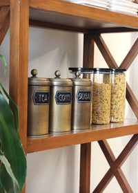 A set of three cylindrical gold-colored canisters with lids, labeled 'Coffee', 'Sugar', and 'Tea' respectively