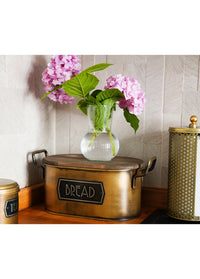 A gold bread bin made from galvanised steel with a wooden lid, hand-painted details, and labeled 'BREAD' on the front.
