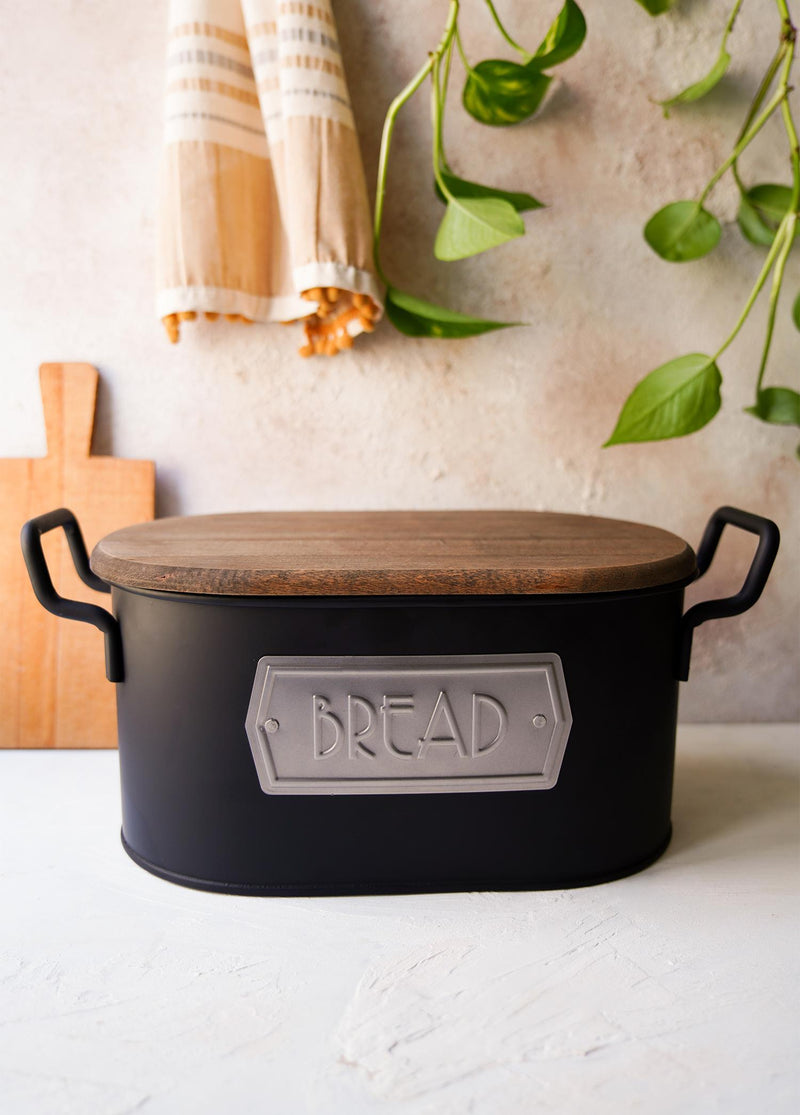 A black bread bin made from galvanised steel with a wooden lid, hand-painted details, and the label 'BREAD' on the front.
