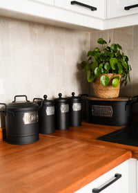 A black bread bin made from galvanised steel with a wooden lid, hand-painted details, and the label 'BREAD' on the front.
