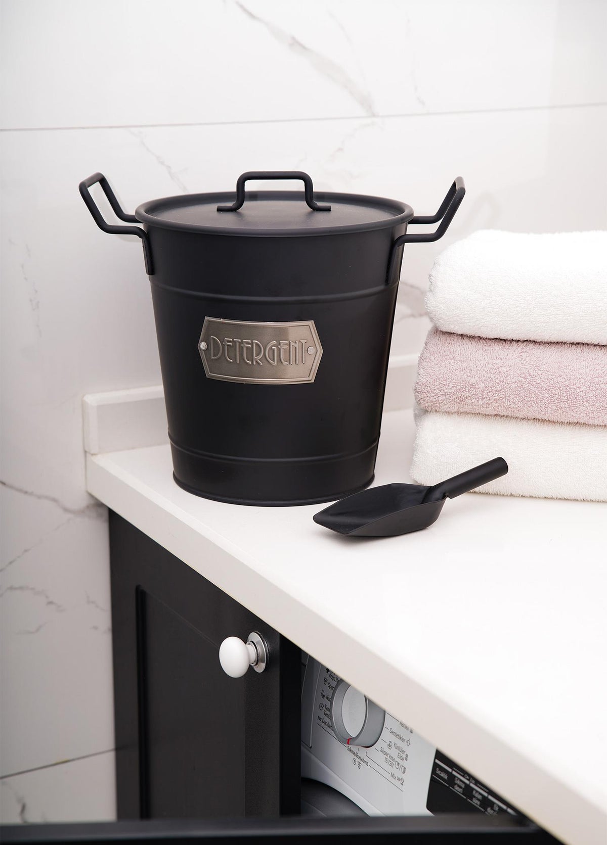 A black galvanised steel washing powder storage box with a lid and utility scoop, featuring a rustic design.
