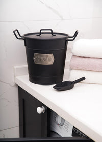 A black galvanised steel washing powder storage box with a lid and utility scoop, featuring a rustic design.
