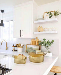 A gold-colored metal bread basket with 'BREAD' embossed on the side, featuring a rustic design with two handles.