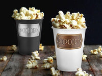 A black galvanised steel popcorn bowl with the word 'POPCORN' printed on the side.